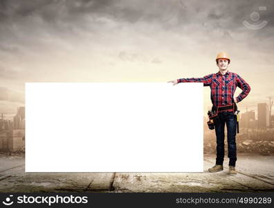 Builder with banner. Young builder man in hardhat holding white blank banner