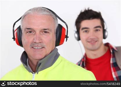 Builder with earmuff stood in front of teenager with headphones