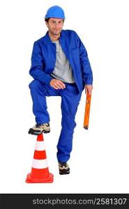 Builder with foot on traffic cone.