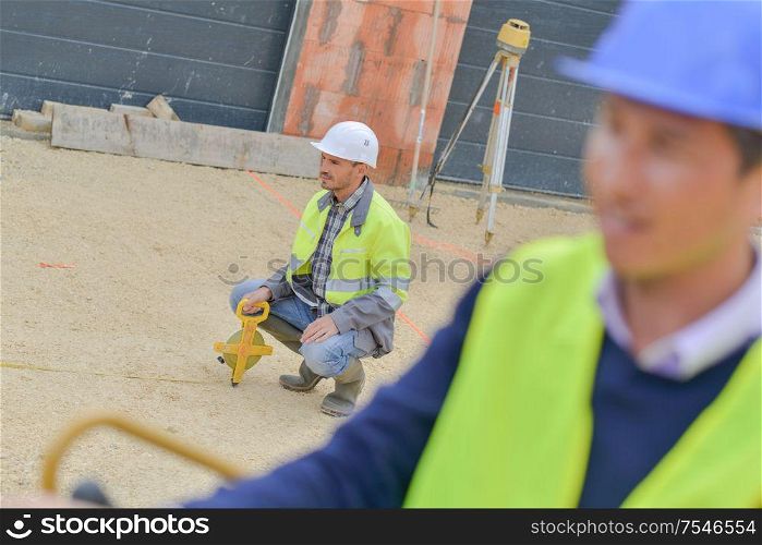 builder with theodolite transit equipment at construction site outdoors