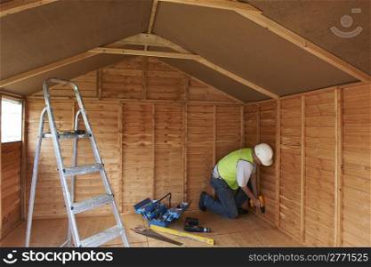 builder working in wooden construction with power tools in protective clothing