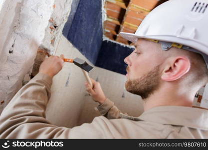 builders using a hammer to remove walls plaster