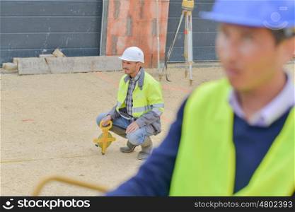 builders using measuring tools outdoors in a construction site