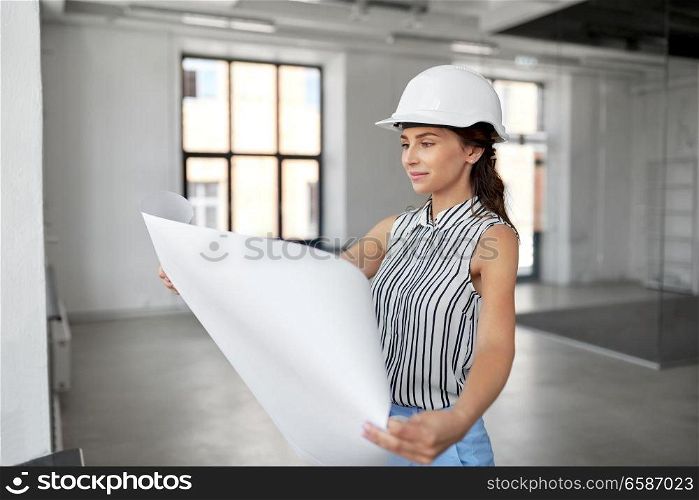 building, architecture and construction business concept - businesswoman or architect in helmet with blueprint at office room. architect in helmet with blueprint at office room