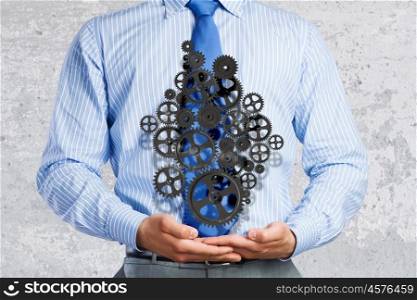 Building business. Close up of businessman holding gears in palms