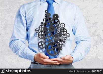 Building business. Close up of businessman holding gears in palms