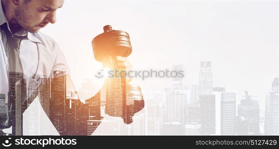 Building business muscles. Hard working business concept. Strong businessman with dumbbell mixed with sunset city skyline