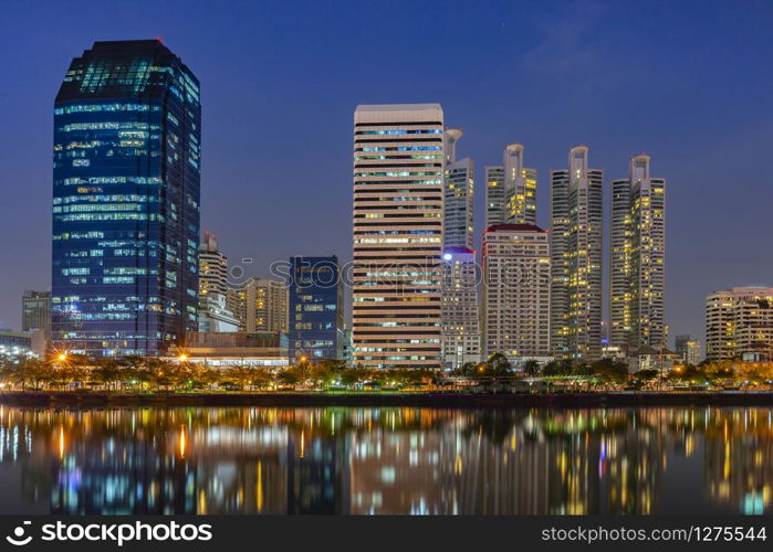 Building city in business area night scene with river reflection in Bangkok, Thailand.