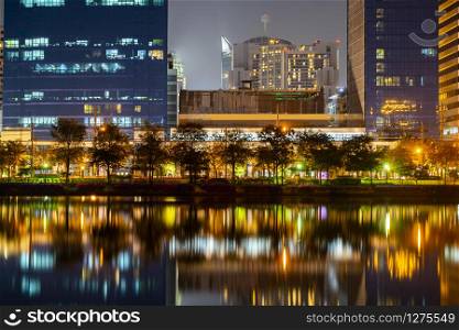 Building city in business area night scene with river reflection in Bangkok, Thailand.