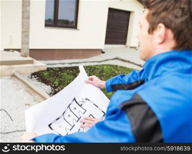 building, construction and people concept - close up of builder with blueprint front of house outdoors