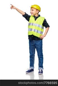 building, construction and profession concept - happy smiling little boy in protective helmet and safety vest pointing finger over white background. little boy in construction helmet pointing finger
