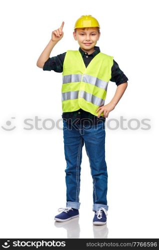 building, construction and profession concept - happy smiling little boy in protective helmet and safety vest pointing finger up over white background. boy in construction helmet pointing finger up