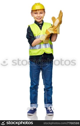 building, construction and profession concept - happy smiling little boy in protective helmet, gloves and safety vest over white background. boy in protective helmet, gloves and safety vest