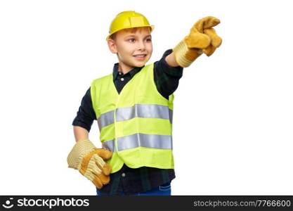 building, construction and profession concept - happy smiling little boy in protective helmet, gloves and safety vest pointing finger over white background. boy in protective helmet, gloves and safety vest