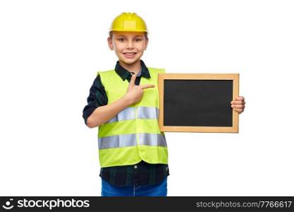 building, construction and profession concept - happy smiling little boy in protective helmet and safety vest holding chalkboard over white background. little boy in protective helmet holding chalkboard