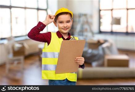 building, construction and profession concept - little boy in protective helmet and safety vest with clipboard over home room background. little boy in construction helmet with clipboard