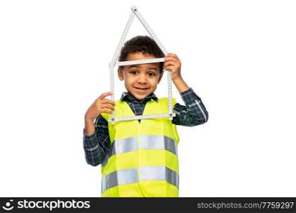 building, construction and profession concept - smiling little boy in safety vest with ruler in shape of house over white background. little boy in safety vest with house made of ruler