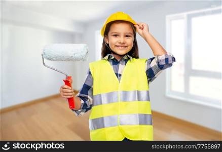 building, construction and profession concept - smiling little girl in protective helmet and safety vest with paint roller over empty room background. girl in helmet and safety vest with paint roller