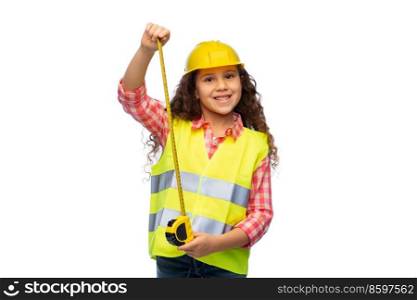 building, construction and profession concept - smiling little girl in protective helmet and safety vest with ruler over white background. little girl in construction helmet with ruler