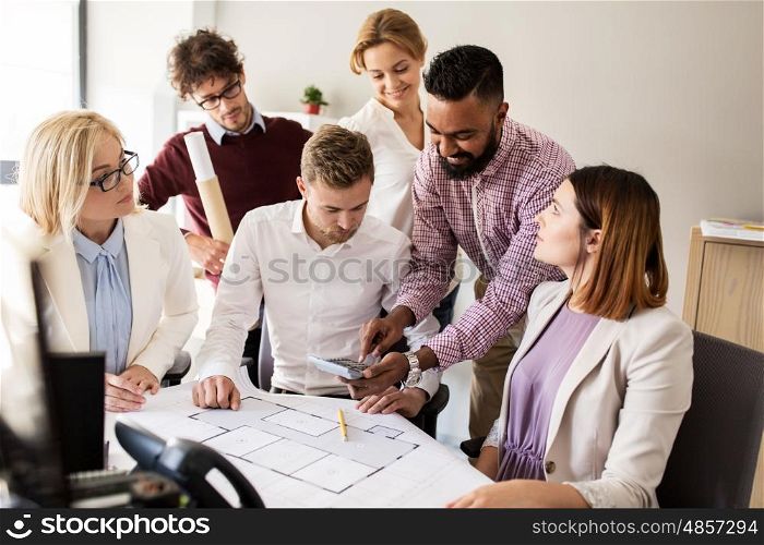 building, construction, architecture, real estate and people concept - business team with blueprint and calculator working with house project at office