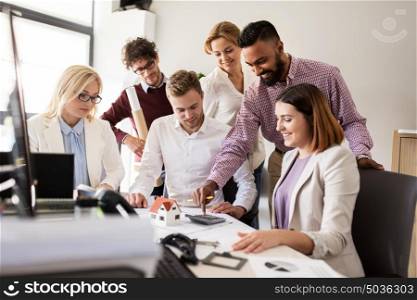 building, construction, architecture, real estate and people concept - business team with blueprint and calculator working with house project at office. business team discussing house project at office