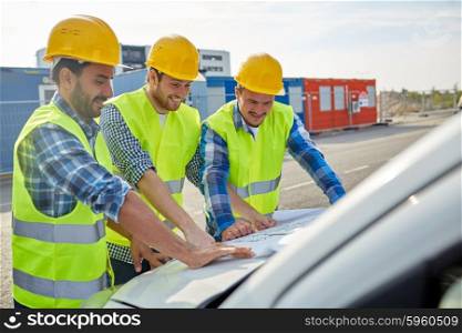 building, construction, development, teamwork and people concept - close up of builders in hardhats and high visible vests with blueprint on car hood