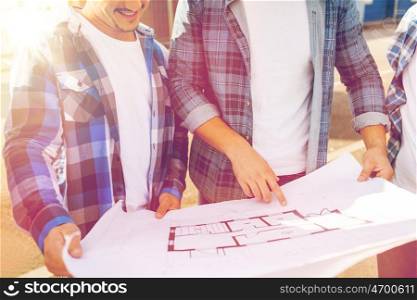 building, construction, development, teamwork and people concept - close up of two smiling builders with blueprint outdoors