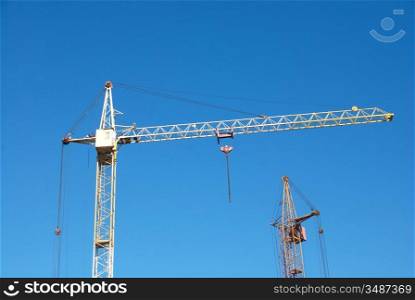 Building crane and building under construction on blue cloudy sky