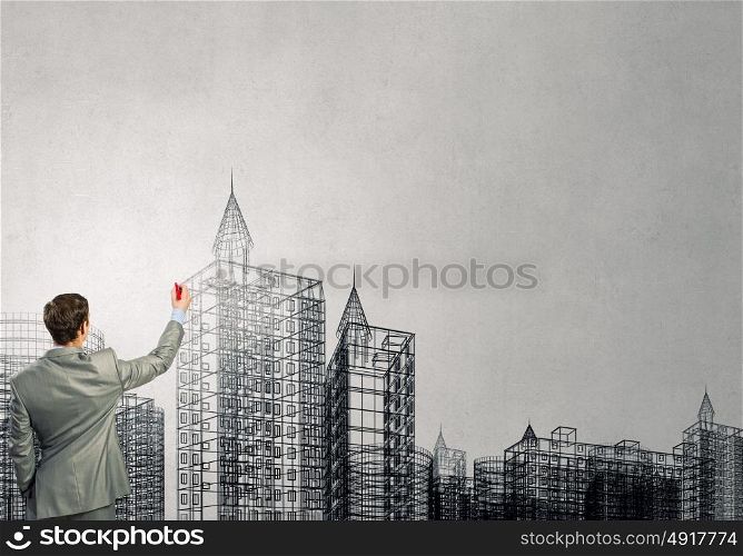 Building design. Back view of businessman drawing sketches of construction project on wall
