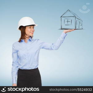 building, developing, advertising and architecture concept - friendly young smiling businesswoman in white helmet holding something on palm