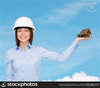 building, developing, advertising and architecture concept - friendly young smiling businesswoman in white helmet holding house on palm