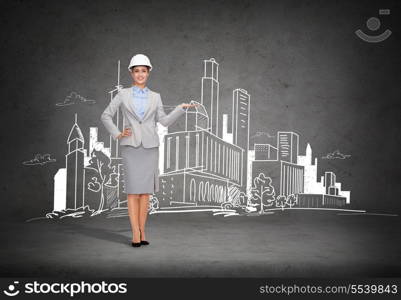 building, developing, advertising and architecture concept - friendly young smiling businesswoman in white helmet showing town drawing