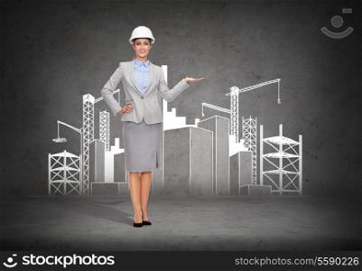 building, developing, advertising and architecture concept - friendly young smiling businesswoman in white helmet showing construction site
