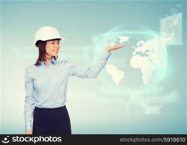 building, developing, advertising and architecture concept - friendly young smiling businesswoman in white helmet holding something on palm