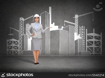 building, developing, advertising and architecture concept - smiling businesswoman in white helmet showing scketch of construction site