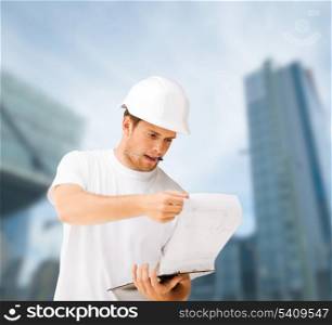 building, developing, consrtuction and architecture concept - male architect in helmet looking at blueprint