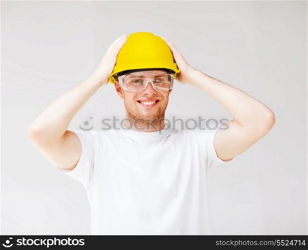 building, developing, consrtuction and architecture concept - picture of male builder in safety glasses and yellow helmet