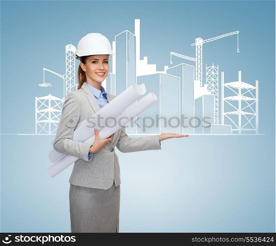 building, developing, consrtuction and architecture concept - smiling architect in helmet with blueprints showing city sketching on palm of hand