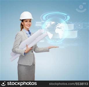 building, developing, consrtuction and architecture concept - smiling architect in helmet with blueprints showing globe hologram on palm of hand