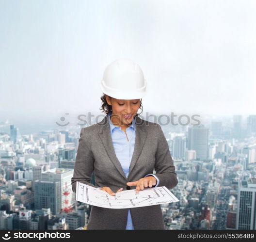 building, developing, consrtuction and architecture concept - smiling businesswoman in white helmet pointing finger to blueprint