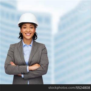 building, developing, consrtuction and architecture concept - smiling businesswoman in white helmet with crossed arms