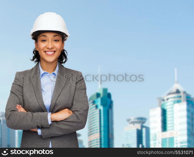 building, developing, consrtuction and architecture concept - smiling businesswoman in white helmet with crossed arms