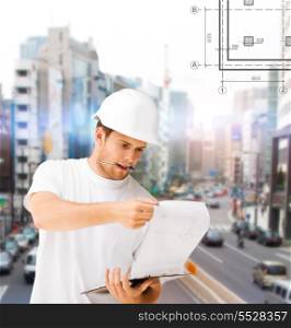 building, developing, construction and architecture concept - male architect in helmet looking at blueprint