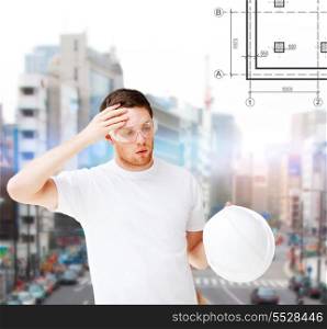 building, developing, construction and architecture concept - male architect in safety glasses taking off helmet