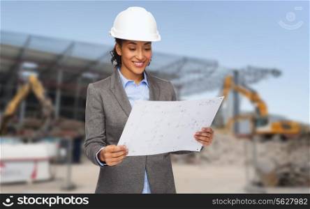 building, developing, construction and architecture concept - smiling african american businesswoman in white helmet looking at blueprint