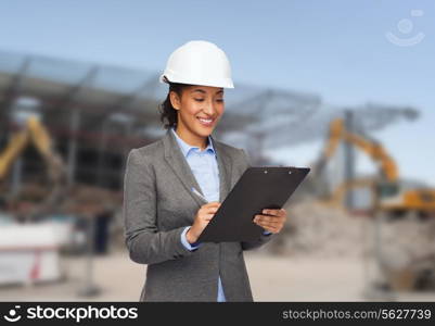 building, developing, construction and architecture concept - smiling african american businesswoman in white helmet with clipboard