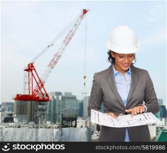 building, developing, construction and architecture concept - smiling businesswoman in white helmet pointing finger to blueprint