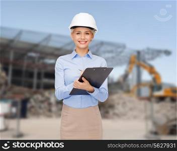 building, developing, construction and architecture concept - smiling businesswoman in white helmet with clipboard