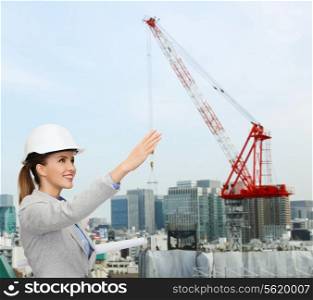 building, developing, construction and architecture concept - smiling woman in white helmet with blueprint