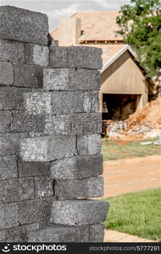 Building material stacked next to the imcomplete house that it is intended for.